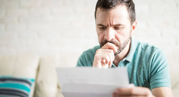 Un jeune homme consulte un avis d'imposition en réfléchissant
